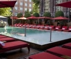 pool surrounded by red lounge chairs