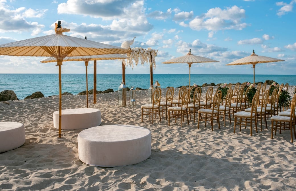 chairs and umbrellas set up on the beach for a wedding ceremony